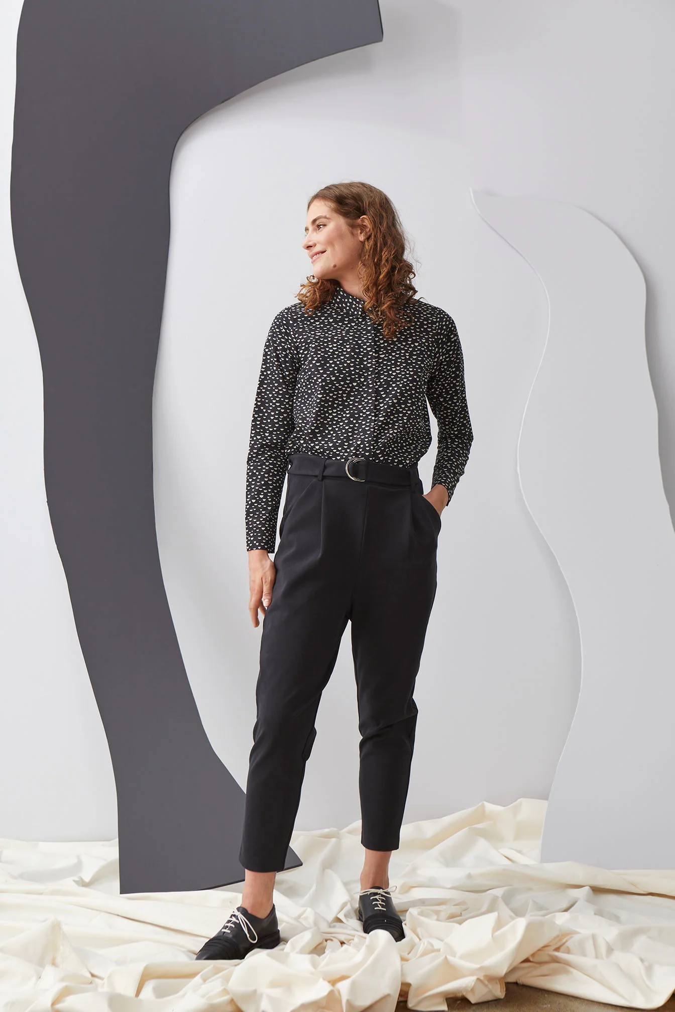 Woman wearing button-up black and white shirt tucked into black fitted pants