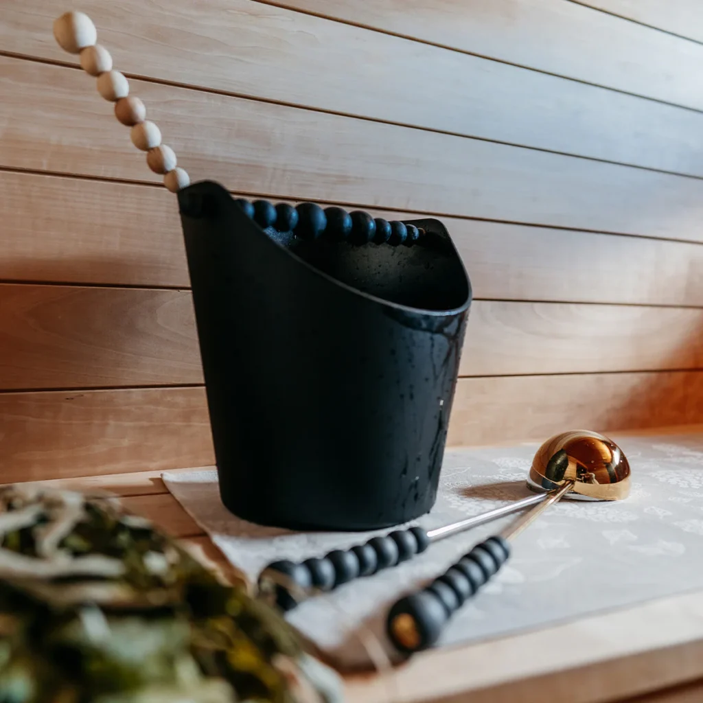 An image showing an Aarikka sauna bucket and ladles on a sauna bench