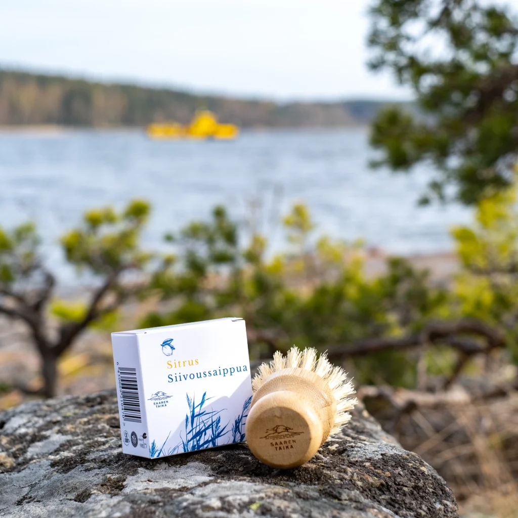 An image of Saaren Taika's eco-friendly cleaning soap and brush on a rock