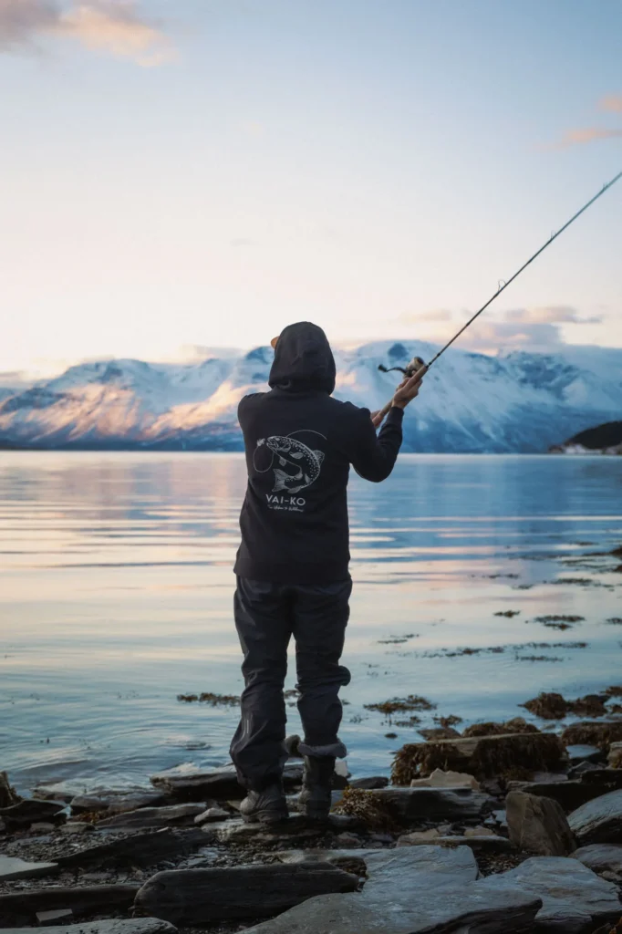 Image of a man at a mountain lake wearing VAI-KO clothing while fishing.